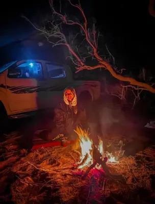 a person standing next to a campfire at night at Wadi Rum sleeping in the desert in Wadi Rum