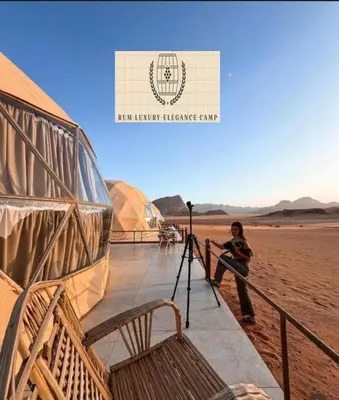 a woman sitting next to a tripod next to tents at RUM ELEGANCE BUBBLE lUXURY CAMP in Wadi Rum
