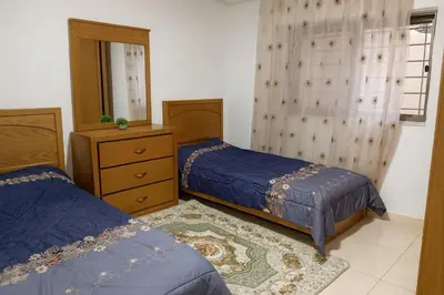 a bedroom with two beds and a dresser and a mirror at Misk Home in Amman