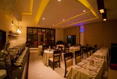 a dining room with tables and chairs with white table linen at Meneur Hotel in Amman