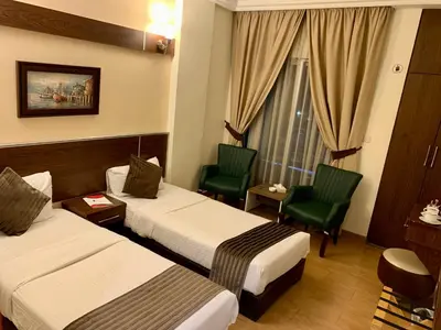 a hotel room with two beds and chairs and a window at Ream Hotel Amman in Amman