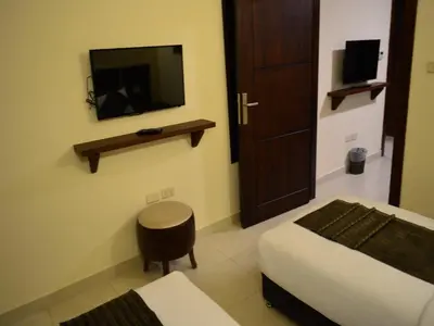 a bedroom with a bed and a tv and a stool at Ream Hotel Amman in Amman