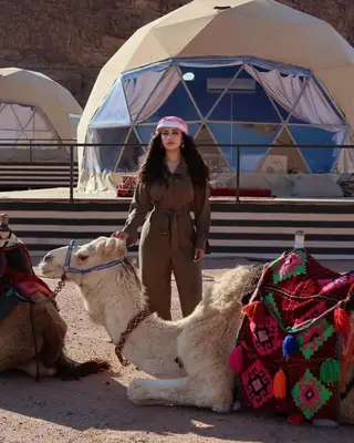 a woman is standing next to a camel at RUM CAMILLA lUXURY CAMP in Wadi Rum