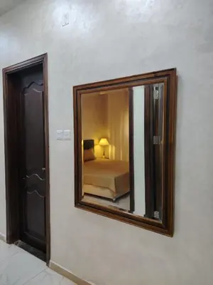 a mirror on a wall with a bed in a bedroom at Al Wesam Furnished Apartments in Aqaba