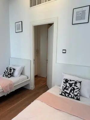 two beds in a room with white walls at DAMAC City View Penthouse in Amman