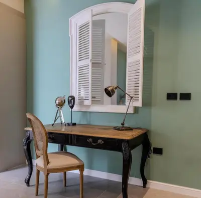 a desk with a mirror and a lamp and a chair at Flamant Apartments in Amman
