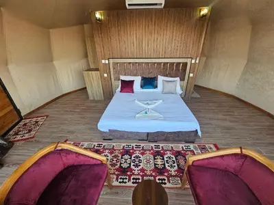 a room with a bed and two chairs in it at Laurana Rum Luxury Camp in Wadi Rum