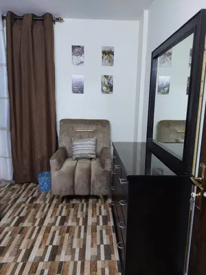 a room with a chair and a dresser and a mirror at New zarqa in Az Zarqa