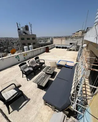 a patio with a table and chairs on a roof at Locations Amman Palm Tree 4 in Ash Shumaysānī