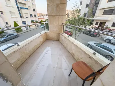 a chair on a balcony with a view of a street at High-end Apartment 2BDR in The most lively AMMAN شقة فاخرة في الدوار السابع in Amman