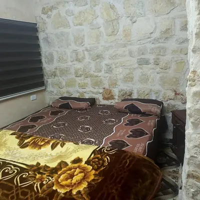 a bed in a room with a stone wall at Dana Moon hostel in Dana