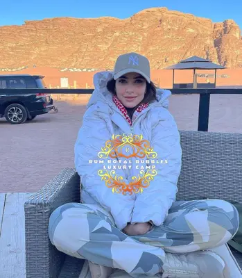 a woman is sitting on a bench in the desert at RUM ROYAL BUBBlES LUXURY CAMP in Wadi Rum