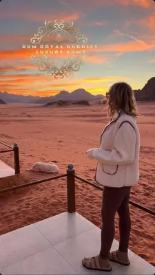 a woman standing next to a fence in the desert at RUM ROYAL BUBBlES LUXURY CAMP in Wadi Rum