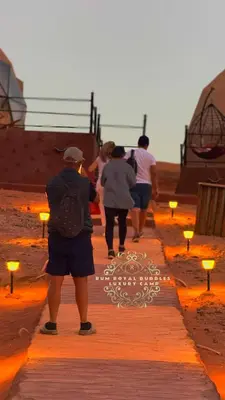 a man taking a picture of people walking on the beach at RUM ROYAL BUBBlES LUXURY CAMP in Wadi Rum