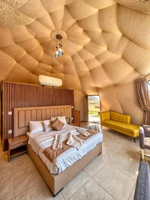 a bedroom with a large bed with a wooden ceiling at Wadi Rum party luxury camp in Disah