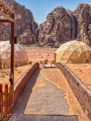 two domes in the desert with a mountain in the background at Wadi Rum party luxury camp in Disah