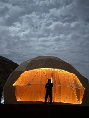 a person standing in front of a large tent at WADI RUM STAR LOTE LUXURY CAMp & BUBBLES ROOM in Wadi Rum