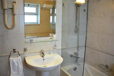 a bathroom with a sink and a shower with a mirror at فندق أميري سويت in Umm Uthainah