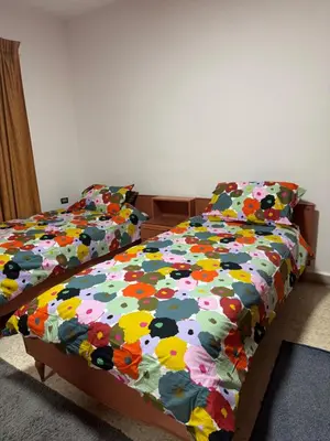 a bedroom with two beds with a colorful comforter at Abdoun apartment with a garden in Amman