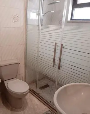 a bathroom with a shower and a toilet and a sink at Abdoun apartment with a garden in Amman