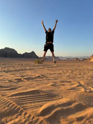 a man jumping in the sand in the desert at Wadi Rum murahf camp in Wadi Rum