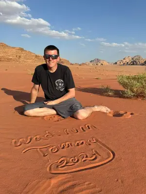 a man sitting in the desert drawing in the sand at Wadi Rum murahf camp in Wadi Rum