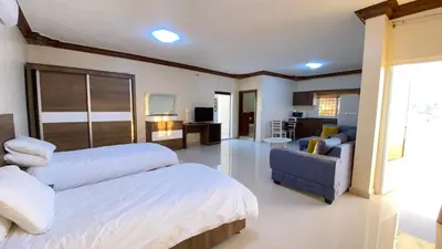a bedroom with two beds and a couch and a chair at Petra EcoStay in Wadi Musa