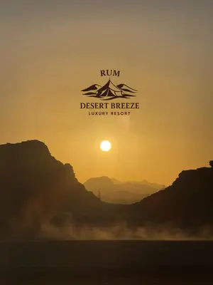 a sunset in the desert with the sun in the sky at RUM DESERT BREEZE lUXURY CAMP&JEEP TOUR in Wadi Rum