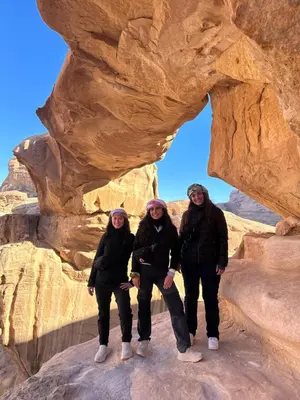 a group of people standing in front of a rock formation at RUM DESERT BREEZE lUXURY CAMP&JEEP TOUR in Wadi Rum