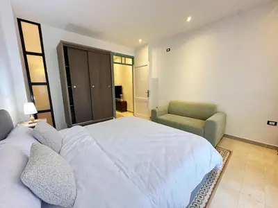 a bedroom with a white bed and a chair at Old Town Charming Two-Bedroom Flat in Amman