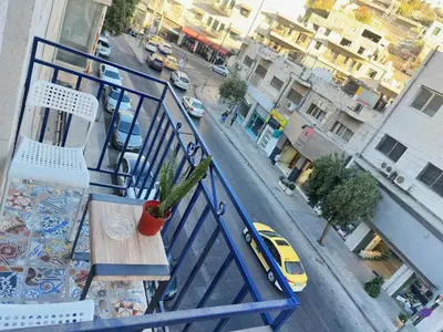 a balcony with a table and chairs and a street at Old Town Charming Two-Bedroom Flat in Amman
