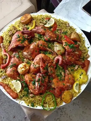 a plate of food with chicken and rice on a table at اذرح فارم in Udhruḩ