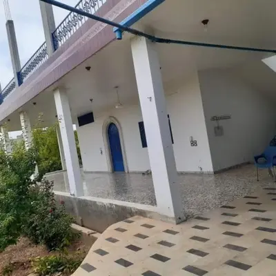 a white building with a blue door and a porch at سموع فارم in Sammū‘
