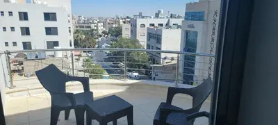 a balcony with two chairs and a view of a city at العبد للشقق الفندقية in Amman
