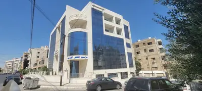 a large glass building with cars parked in front of it at العبد للشقق الفندقية in Amman