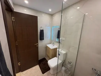 a bathroom with a toilet and a glass shower at Third circle Luxury Hotel apartment New in Amman