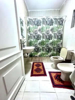 a bathroom with a toilet and a green plant wallpaper at 3 Bedrooms Cozy Apartment Prime Location Walk Anywhere شقة مفروشة واسعة شارع الجاردنز in Amman