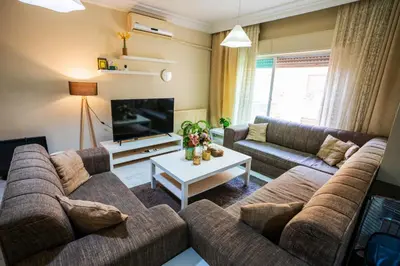 a living room with a couch and a tv at 3 Bedrooms Cozy Apartment Prime Location Walk Anywhere شقة مفروشة واسعة شارع الجاردنز in Amman