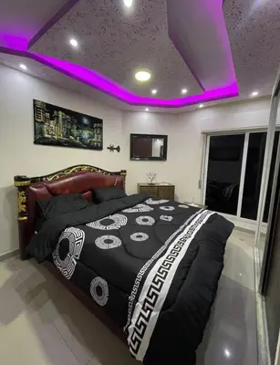 a bedroom with a black and white bed with purple lights at Falcon Real Estate in Amman
