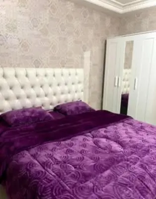 a bedroom with a purple bed with a white headboard at Falcon Real Estate in Amman