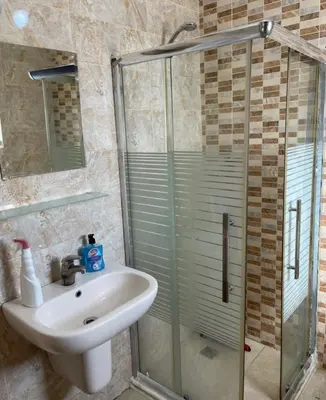 a bathroom with a sink and a glass shower at Falcon Real Estate in Amman