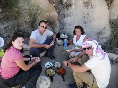 a group of people sitting around a table with food at Dana Valley Tourism Hotel in Dana