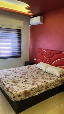 a bedroom with a large bed with a red wall at Izz AlDin Tamimi St, Deluxe Jubaiha Furnished Apartment,3rd Edition in Amman