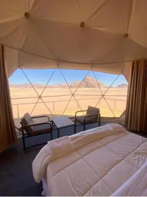 a bedroom with a bed and a view of the desert at Rum gate camp Fares in Disah