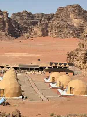 a group of tents in the desert with a mountain at Ayla Rum Luxury Camp in Wadi Rum