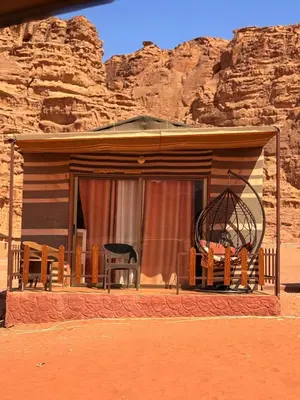 a house with two chairs and a window in the desert at Ayla Rum Luxury Camp in Wadi Rum