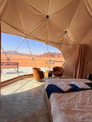 a bedroom with a bed in a tent with a view at Ayla Rum Luxury Camp in Wadi Rum