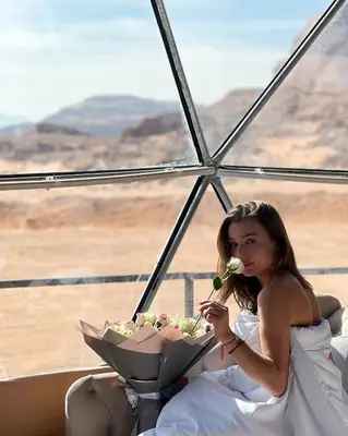 a woman in a white dress holding a bouquet of flowers at Wadi Rum Hala camp in Wadi Rum