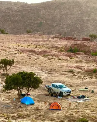 a car parked in the middle of a desert with tents at Dana Hiking Camp - Dana Nature Reserve in Dana