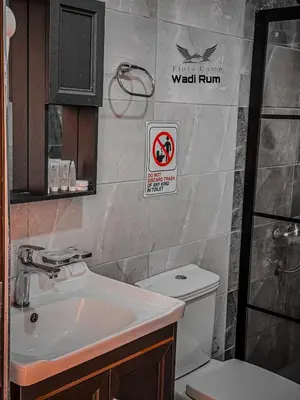 a bathroom with a sink and a toilet and a sign at Flora Camp Wadi Rum in Wadi Rum